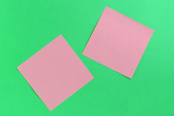 Empty pink sticker notes on a green background. Business concept, horizontal mock-up