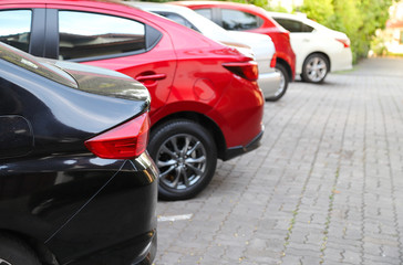 Closeup of rear, back side of black car with  other cars parking in outdoor parking area  with natural background in bright sunny day. 