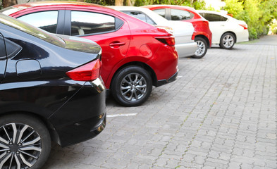 Closeup of rear, back side of black car with  other cars parking in outdoor parking area  with natural background in bright sunny day. 