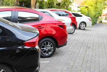 Closeup of rear, back side of black car with  other cars parking in outdoor parking area with natural background in sunny day. 
