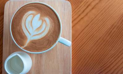 In the morning, Latte coffee cup with latte art on wooden table in coffee shop.