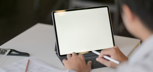 Close-up view of young professional architect working on his project with mock up tablet in modern office