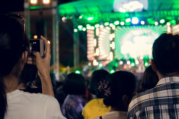 Fototapeta na wymiar People use mobile phones to live or take pictures at concerts, with bright lights at night.