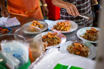 The cook is preparing the dishes of pad thai in the kitchen.