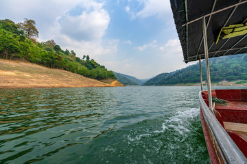a take boat at beautiful blue sky green forest mountains lake view at Kaeng Krachan National Park, Thailand.  an idea for backpacker hiking on long weekend