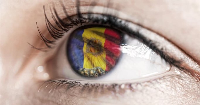 Woman green eye in close up with the flag of andorra in iris with wind motion. video concept