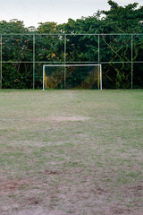 soccer posts in park, field is partially covered in the shadow. Trees in the background are in the sun. Rio de Janeiro, Brazil.