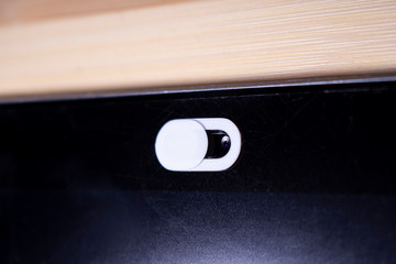 Close up of a White Camera Privacy Cover Slide, Webcam Cover for smart device on a wooden table