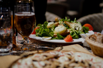 Goat cheese salad on table with beer and other delicious itens out in the sun, blurred foreground. Colmar, Alsace