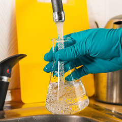 water purification specialist tap water pours into a glass flask.
