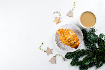 Christmas breakfast. Cup of coffee, croissant and holiday decoration toys, tree fir branches on white table. background. Top view, flat lay, copy space