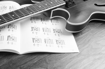 Electric guitar and chord book on a wooden texture