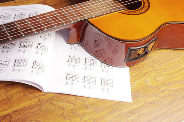 Fototapeta na wymiar Acoustic guitar and chord book on a wooden texture