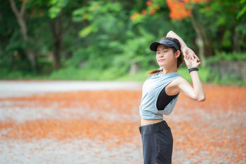 Portrait of runner woman doing stretching and warming up her body before running in the park. The benifit of stretching can increasing flexibility performance and reduce risk of injury. 