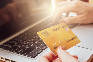 Close up of someone hand holding credit card during using laptop for online shopping. Online shopping is the process of buying goods and services from merchants over the Internet. 