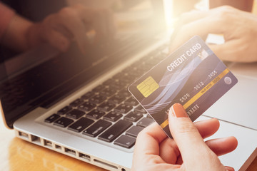 Close up of someone hand holding credit card during using laptop for online shopping. Online shopping is the process of buying goods and services from merchants over the Internet. 