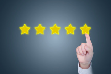 A businessman finger clicks on five stars, reviews, improves ratings or rankings, evaluates and...
