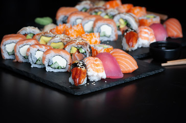 Sushi set with nigiri sushi, uramaki California, Philadelphia, Unagi rolls on black stone plate.