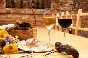 Still life with two glasses with red and white wine on wooden table in the old vintage wine cellar from red brick
