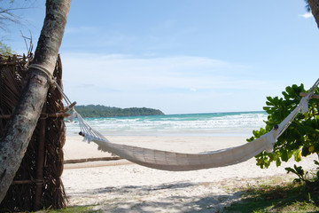 Fototapeta na wymiar A white hammock with a rope tied to a coconut tree for relaxing on the beach.