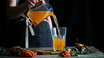 Herbal sea buckthorn tea pouring from glass teapot into the glass. Seamless cinemagraph looped video