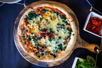 Homemade spinach pizza with mozzarella with decorative light