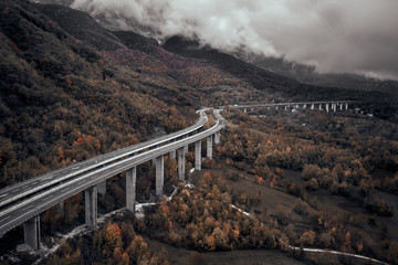High autumn alpine speed road in Italia. Aerial view from above with clouds on the background