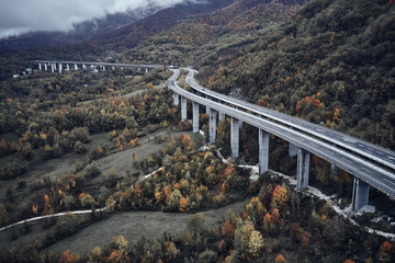 High autumn alpine speed road in Italia. Aerial view from above with clouds on the background