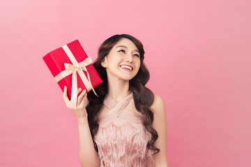 Young woman holding gift box with biege bow being excited and surprised holiday present