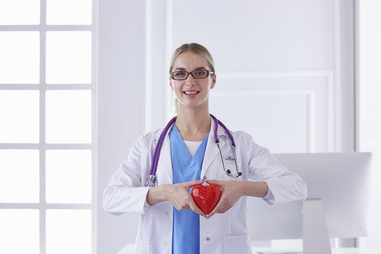 Doctor with stethoscope holding heart, isolated on white backgr