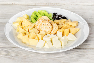 Cheese platter on a white plate on a wooden background