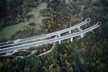 High autumn alpine speed road in Italia with exit or enter into the tunnel. Aerial view from above.