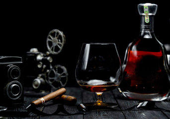 glass of cognac and cigar on a wooden table