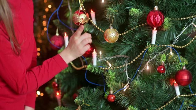 Children's hands decorate the Christmas tree in the room with decorative balls. Preparing for Christmas and New Year. Holidays