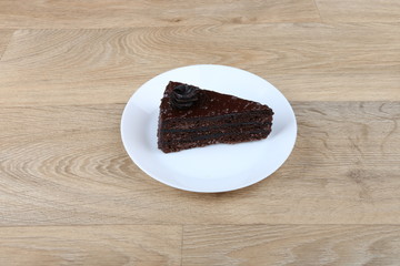  Chocolate cake on a white plate isolated on a wooden background 