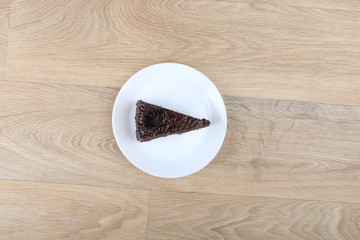  Chocolate cake on a white plate isolated on a wooden background 