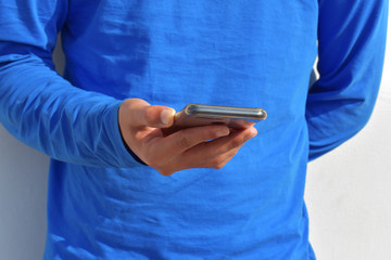 Handsome young man wearing a casual outfit and holding his phone having a chat