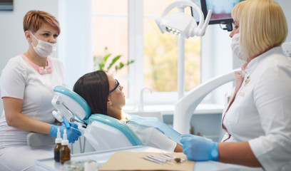 Obraz premium Doctor dentist treats teeth of a beautiful young girl patient.