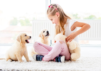Obraz premium Puppies play with cheerful girl