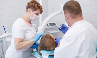 Fototapeta na wymiar Doctor dentist treats teeth of a beautiful young girl patient.