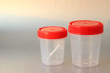 Jars for the collection of analyzes: feces and urine on a gray background with Sunlight.  Selective focus. Prophylactic medical examination.