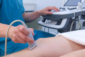 Ultrasound screening of knee joint for man using ultrasound scanner in clinic, closeup view. Doctor...