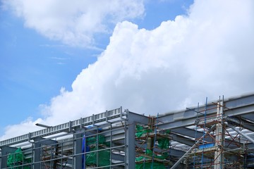 Fototapeta premium The structure of building with blue sky and cloud as a background, Steel construction in large construction site, Space for text in template