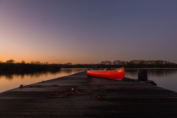 Who wants to go canoeing? The red canoe on the pier at the lake.