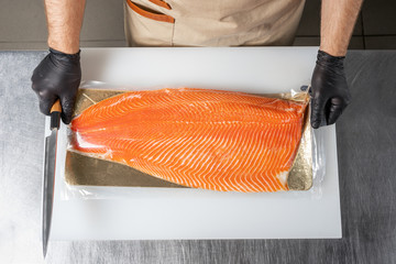 Cook unpacks salmon fillets on a cutting Board. The view from the top.