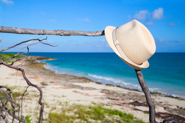 A man's straw hat hangs, lies, on a branch against the beautiful sea.Horizontally.