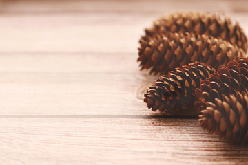 Brown pine cones on a wooden background.  Chocolate toning. Selective focus. Decorative Christmas background.
