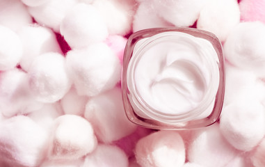 Luxury face cream for sensitive skin and pink cotton balls on background, spa cosmetics and natural...