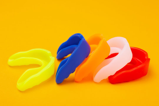 five colored boxing mouth guards laid out in a row on a yellow background, concept