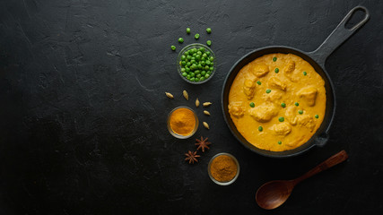 Cooking tasty chicken curry in pan on black background. Flat lay, top view with copy space - obrazy, fototapety, plakaty